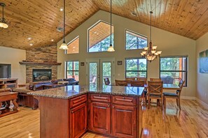 A spacious kitchen with a large island, wooden ceiling, and large windows.