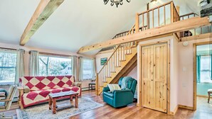 A spacious living room with a wooden staircase, a red and white patterned sofa, and a teal armchair. - Cozy Tannersville Gem - Ski, Hike, Explore! (Tannersville)