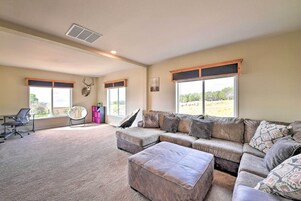 Amplia sala de estar con sofá modular, reposapiés y una butaca. Cuenta con un ventanal con vistas al exterior.