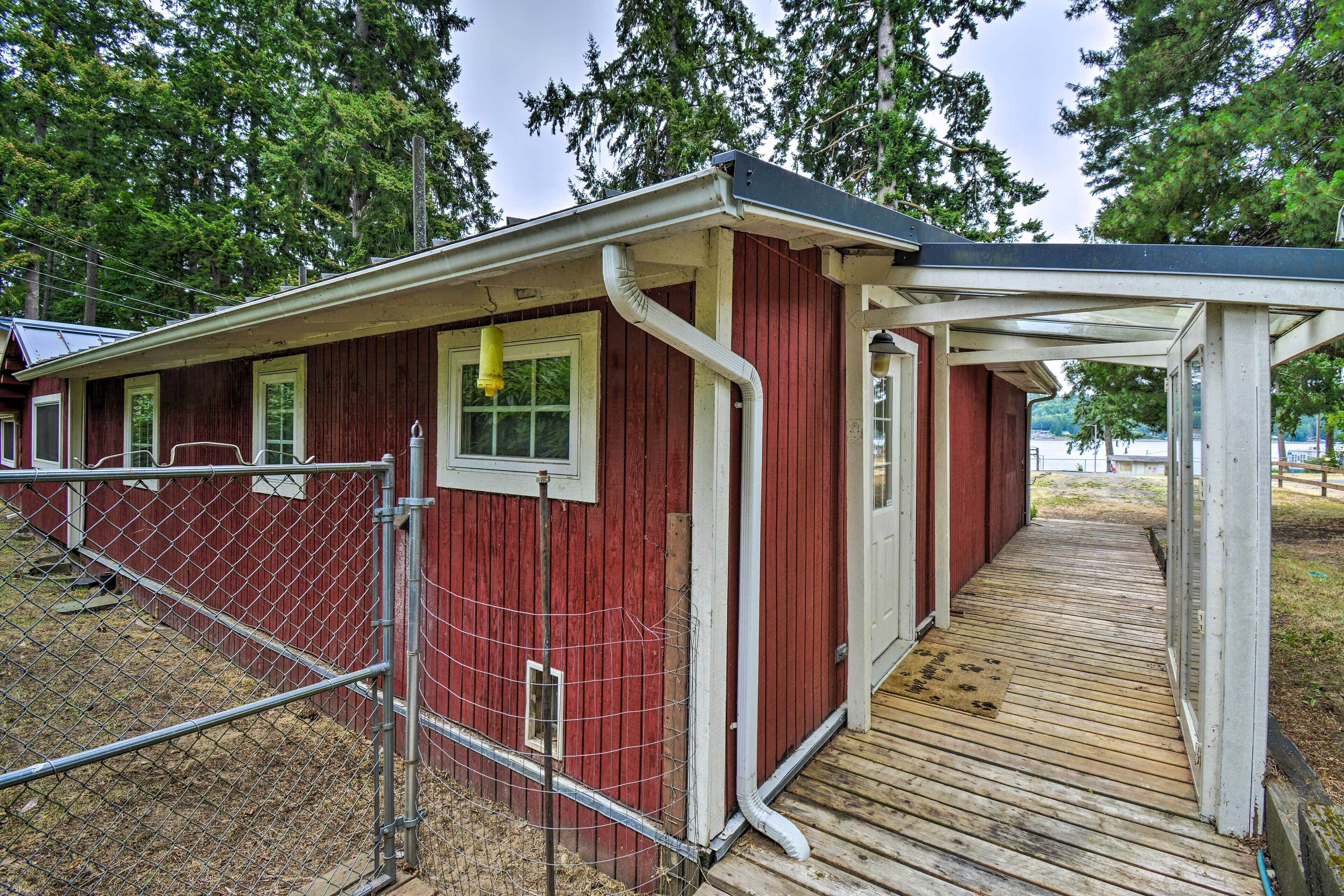 Un bâtiment rouge doté d’une terrasse en bois et d’une zone délimitée par une clôture.