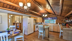Une cuisine rustique avec un plancher en bois, des meubles blancs et un coin repas doté de chaises à rayures.