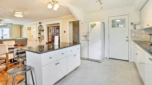 Uma cozinha moderna com armários brancos, uma ilha central e uma geladeira.