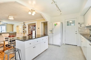 Una cocina moderna con armarios blancos, una isla central y un refrigerador.