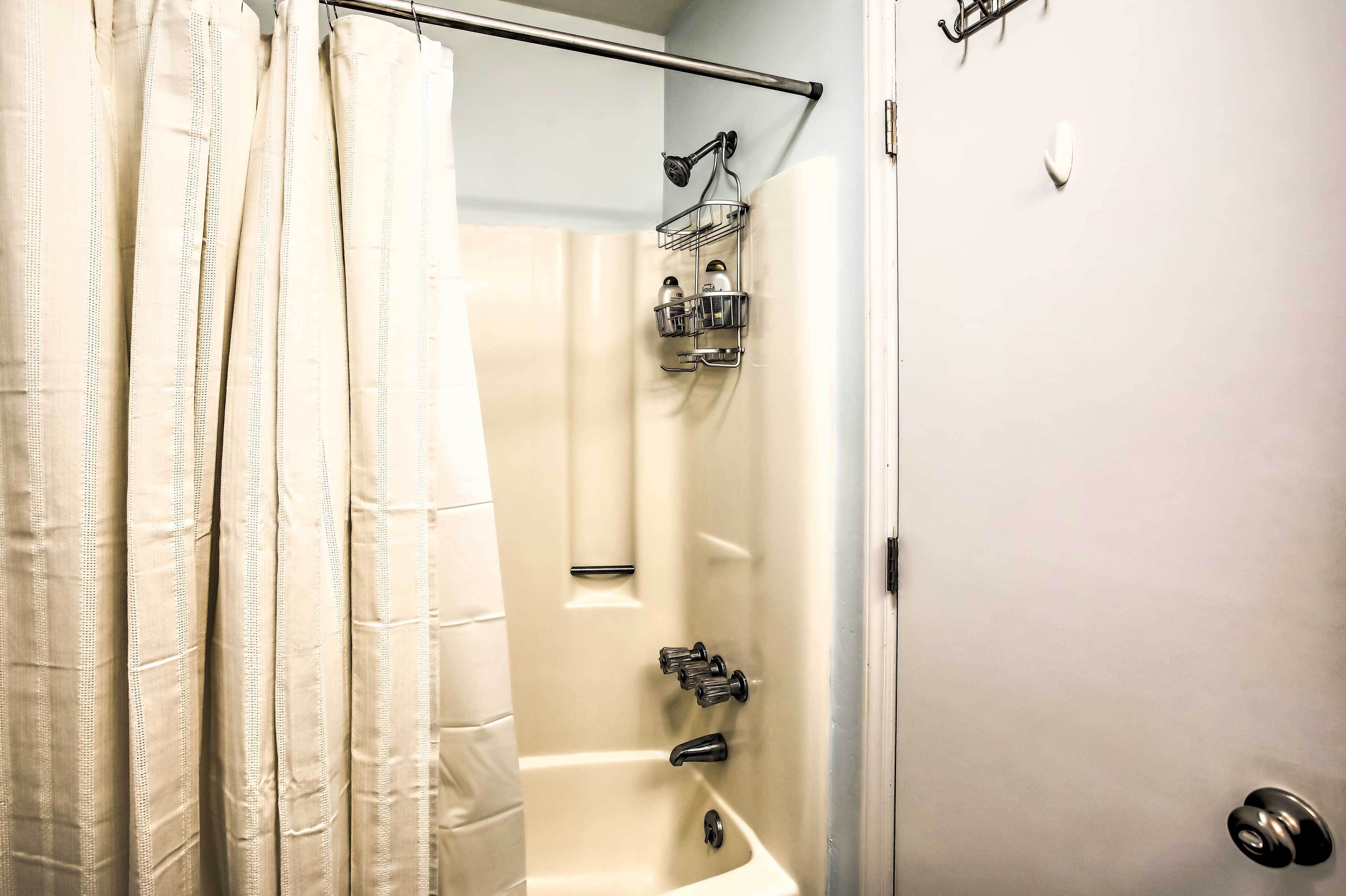 A bathroom with a shower, a bathtub, and a towel rack.