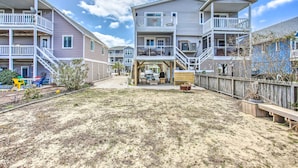 Una zona residencial frente a la playa con varias casas de dos pisos, balcones, patio de arena y cerca de madera.