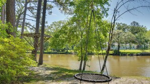 Un espace extérieur paisible, comprenant une balançoire, une petite structure en bois et un plan d’eau.