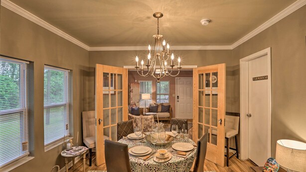 A dining area with a chandelier, wooden doors, and a table set for four.