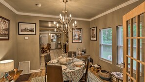 A dining area with a chandelier, framed artwork, and a view of the kitchen.