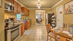 A kitchen with wooden cabinets, a stainless steel microwave, and a dining area with a table set for four.