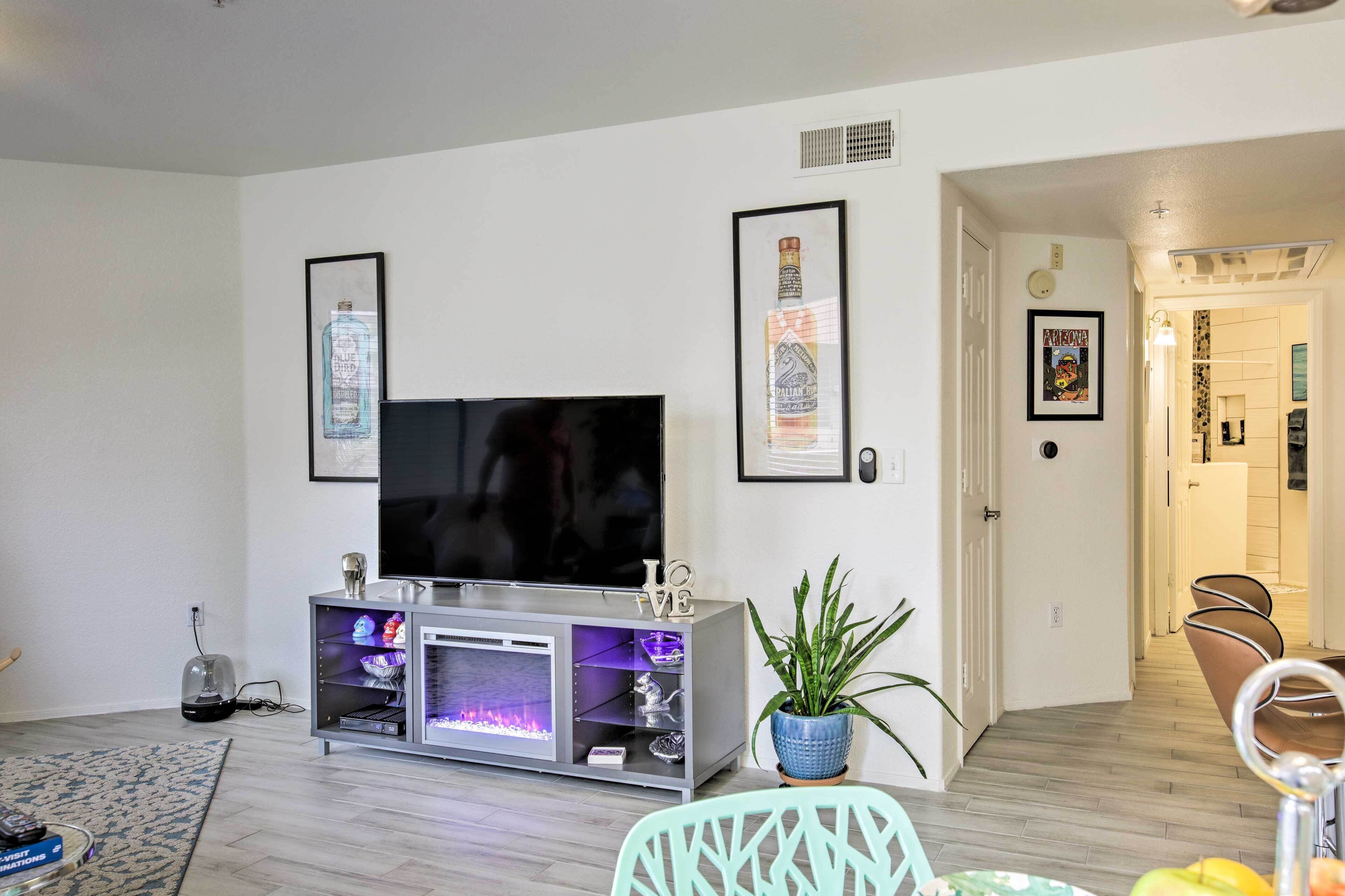 A modern living room with a flat-screen TV, a silver entertainment unit, and a potted plant.