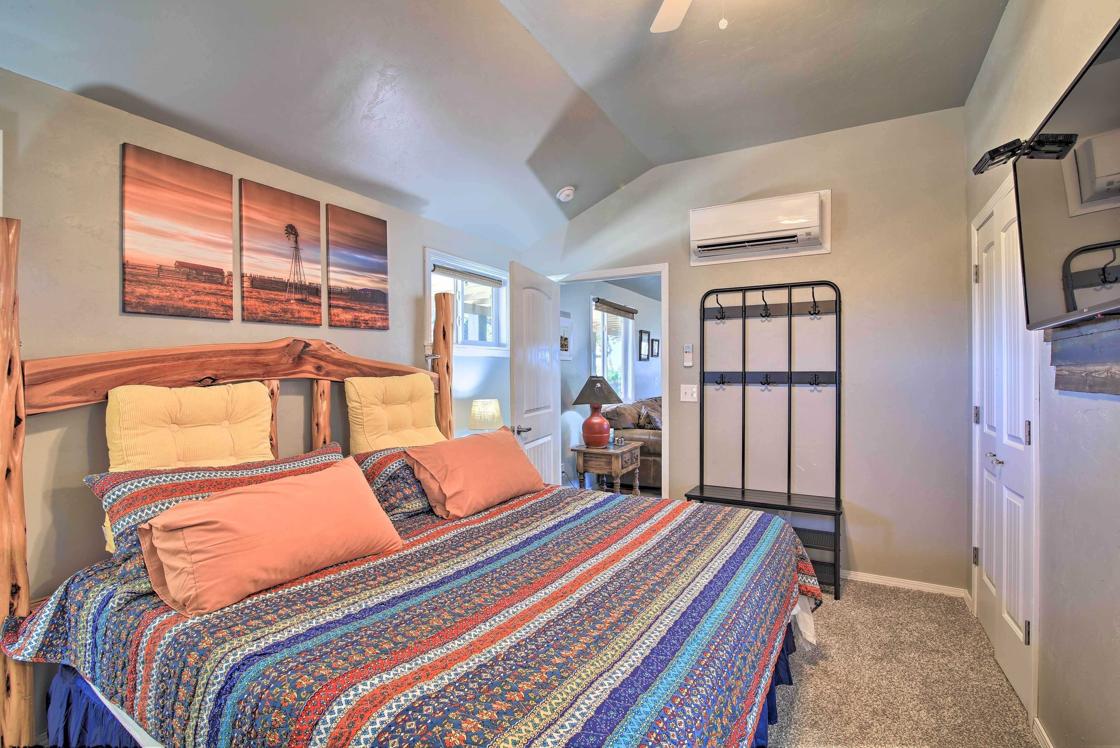 A bedroom with a bed, a headboard, a window, an air conditioning unit, and a door.