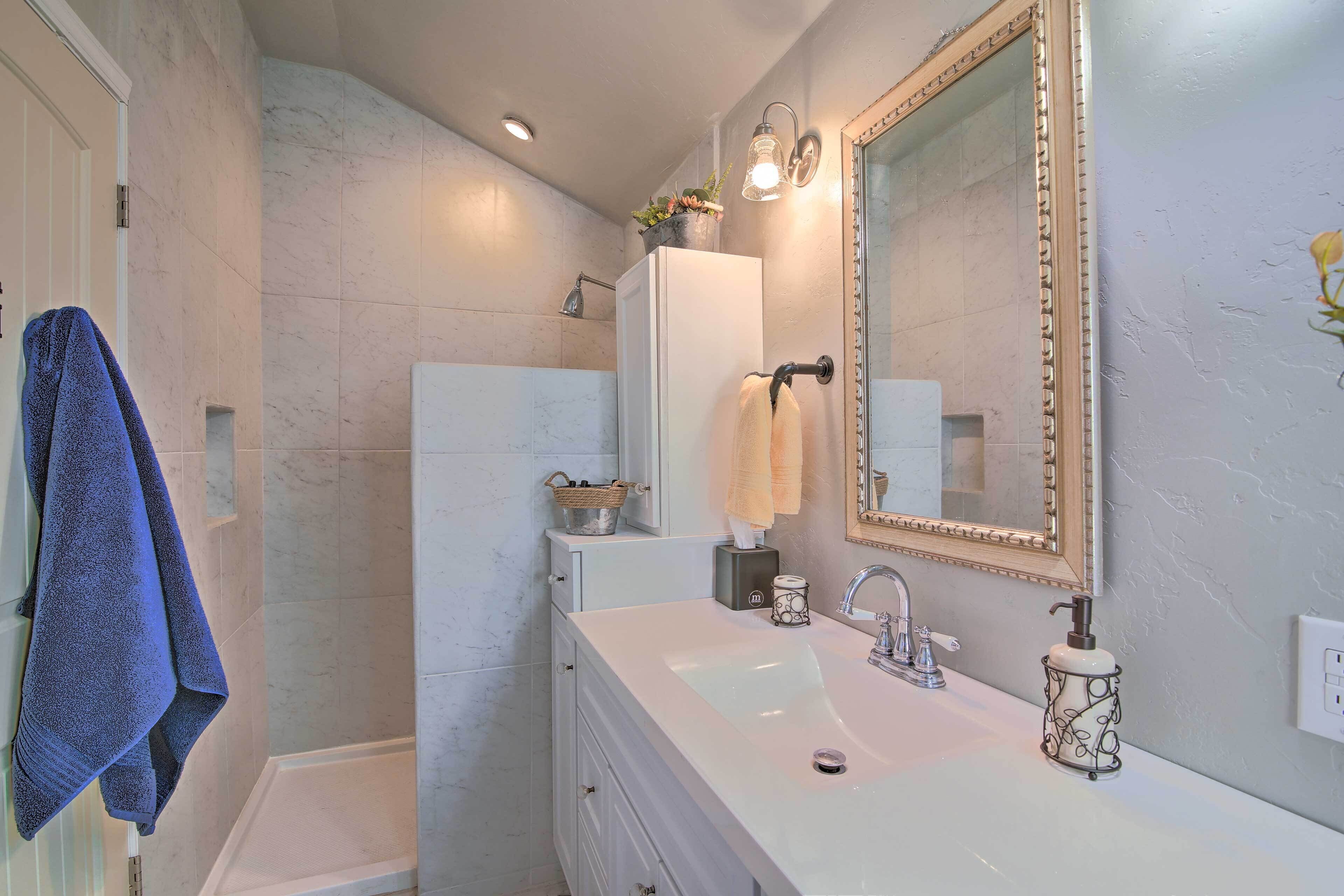 Une salle de bain avec un meuble-lavabo blanc, un grand miroir et un espace douche.