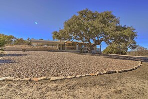 Un bâtiment devant lequel se trouve un grand arbre, le tout étant entouré d’une zone recouverte de gravier.