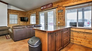 A cabin interior with a sofa, a bar area, and a ski lift sign.