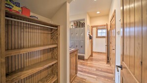 Un pasillo con estantes de madera, varios casilleros y una puerta que da a otra habitación.