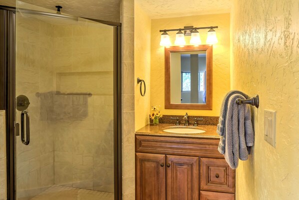 Un baño con cabina de ducha de vidrio, un lavabo con tocador de madera y un espejo con iluminación.