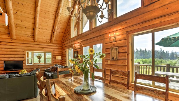 A wooden cabin interior with a dining area, a sofa, and a TV in the living room. - 13 Mi to Mt Shasta: Log Home on 60 Acres! (McCloud)
