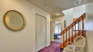 A hallway with a purple carpet, a white door, a white chair, and a wooden staircase. - Townhome w/ Balcony < 1 Mi to Wildwood Crest Bch! (Wildwood Crest)
