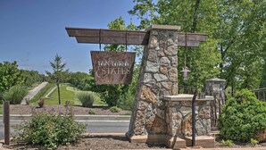Un pilier de pierre surmonté d’une plaque indiquant « TAN-TARA ESTATES », et un paysage bien entretenu avec un terrain de golf en arrière-plan.