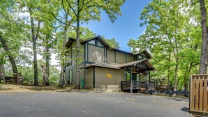 Un chalet doté d’une grande terrasse et d’un espace couvert, entouré de grands arbres.