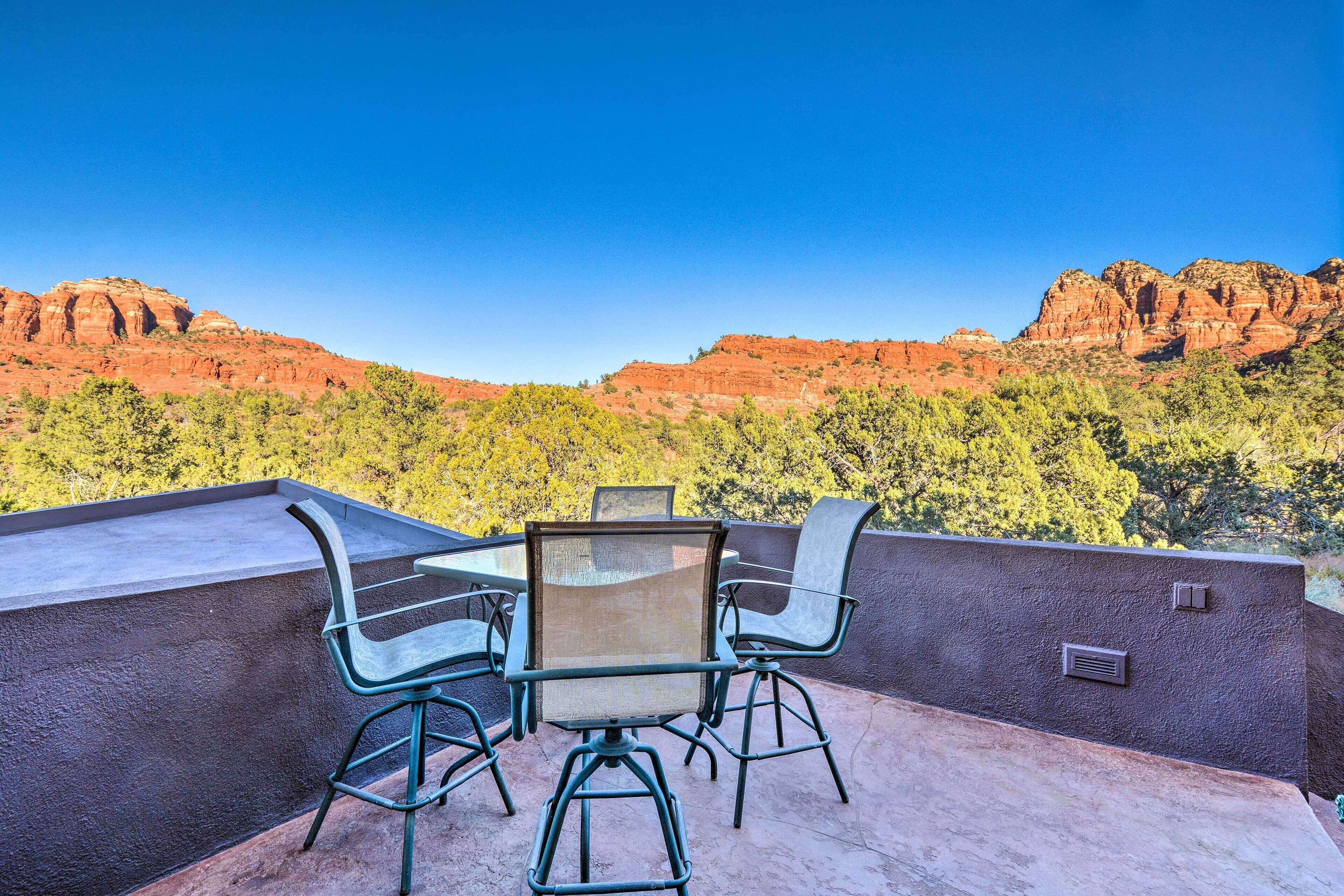 An outdoor patio with a table and chairs, overlooking a mountainous landscape.