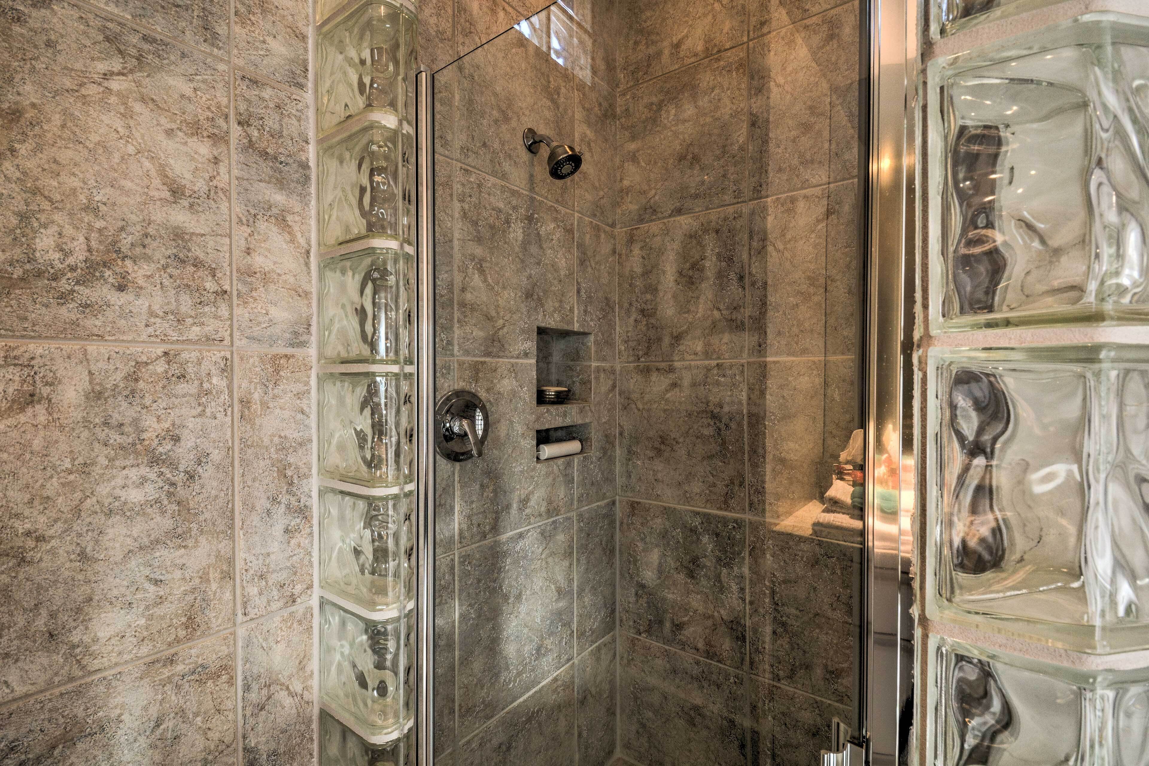 A shower with glass panels and a marble-tiled wall.