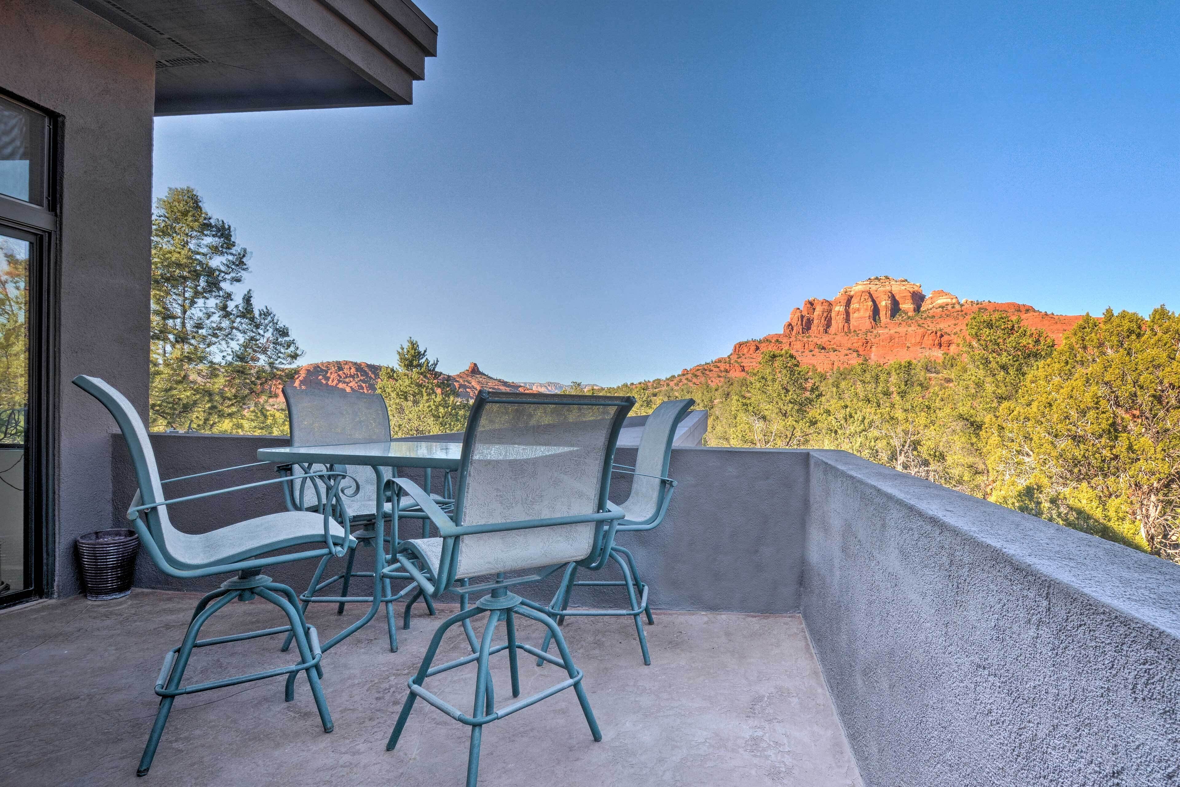Een balkon met een tafel en stoelen, met uitzicht op een bergachtig landschap.