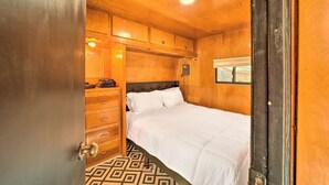 Ein Schlafzimmer aus Holz mit einem Bett, einem Schminktisch und einem Fenster.
