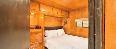 Une chambre à coucher en bois, avec un lit, une commode et une fenêtre.