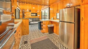 Une cuisine de taille réduite, avec des meubles en bois, un réfrigérateur en acier inoxydable et un tapis à motifs.