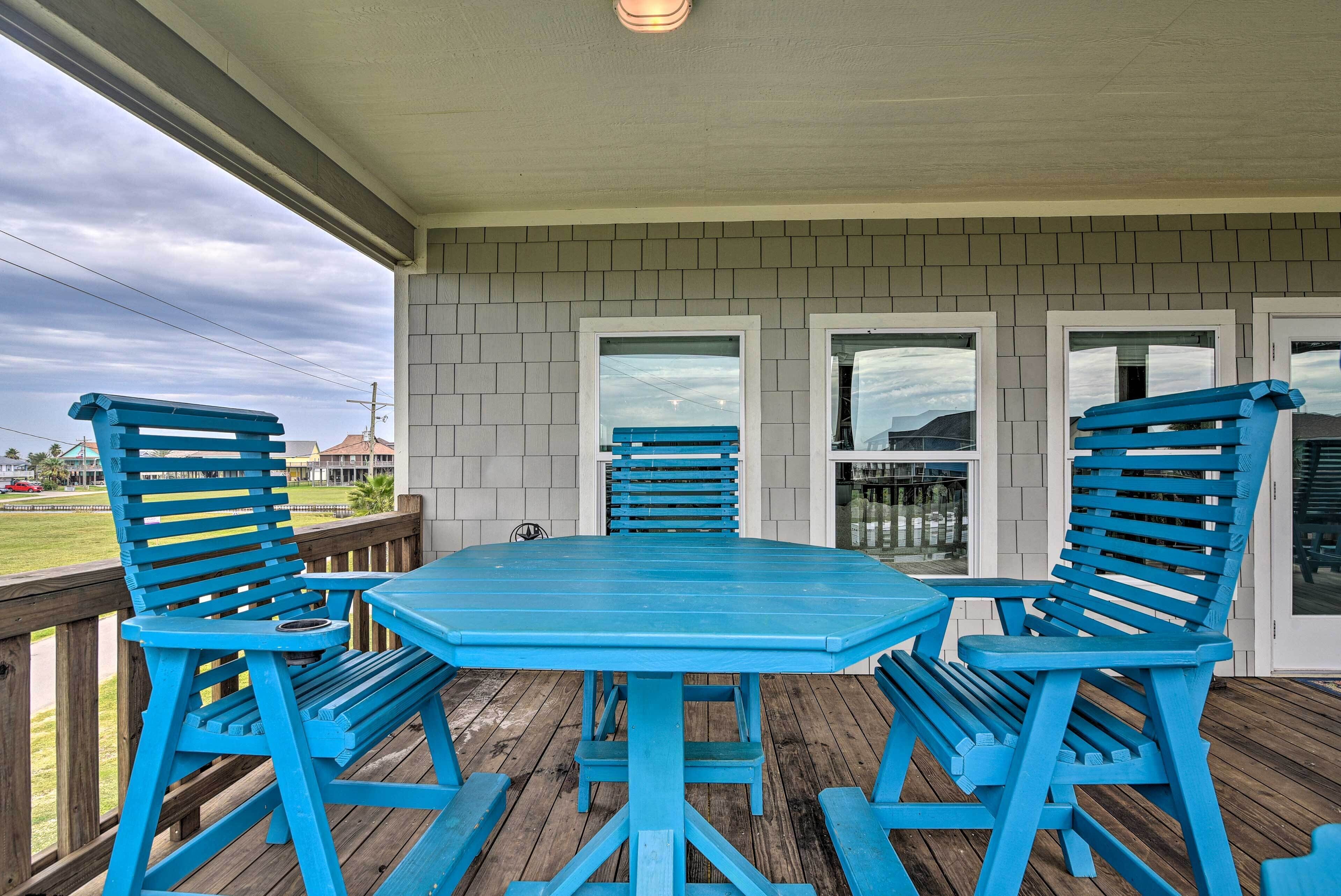 A covered outdoor area with a wooden deck, a blue table, and matching chairs.