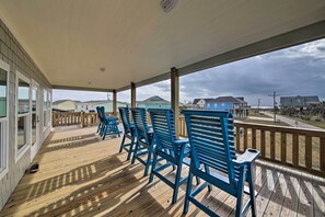 A covered outdoor area with wooden flooring and blue chairs. - Deck & Ocean Views: Home in Crystal Beach! (Port Bolivar)