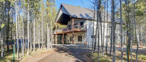 A two-story building with a sloped roof, surrounded by tall trees.
