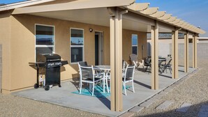 Ein überdachter Patio-Bereich mit Grill, Sitzgelegenheit und Blick auf die umliegende Nachbarschaft.