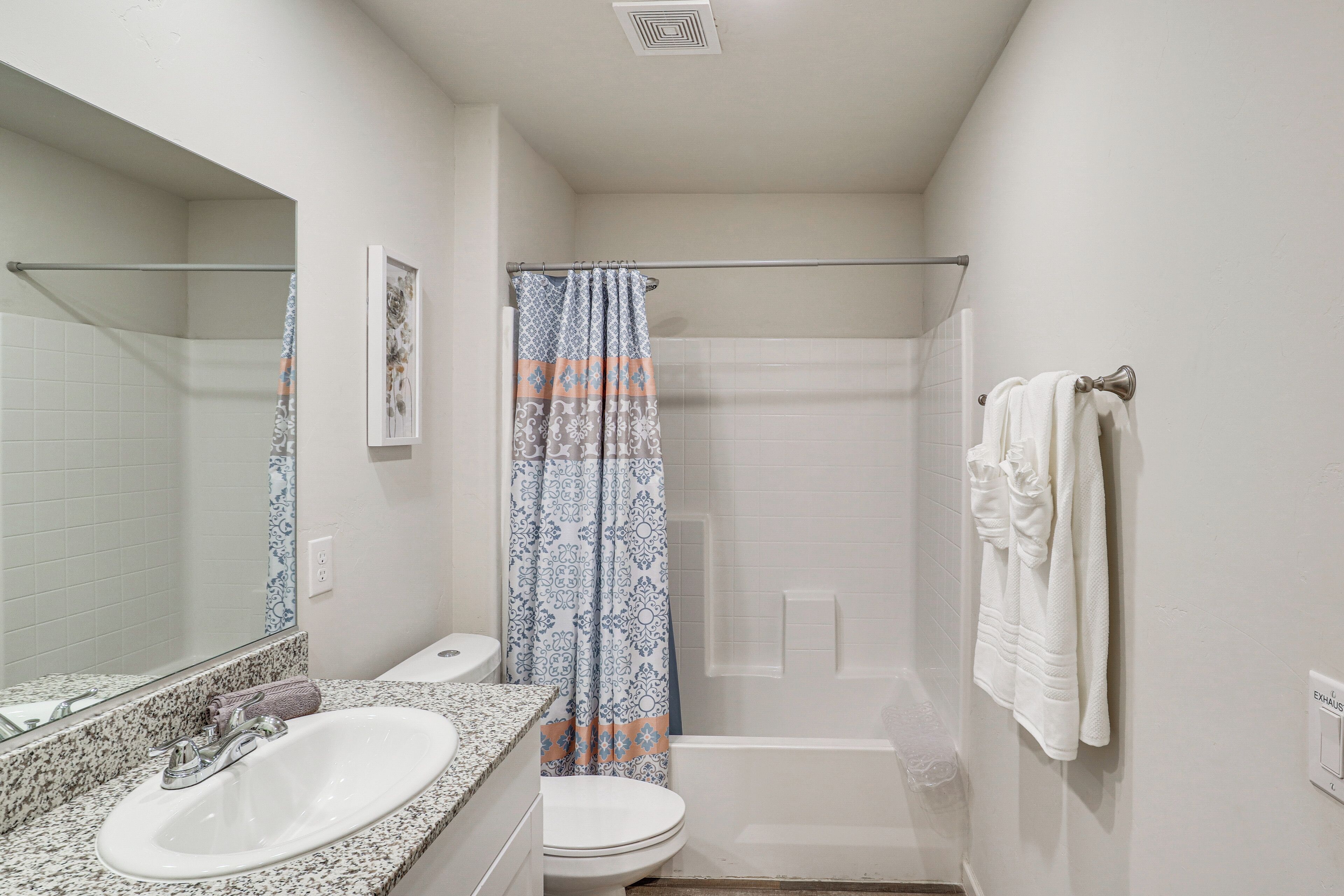 A bathroom with a sink, toilet, shower, and a towel rack.