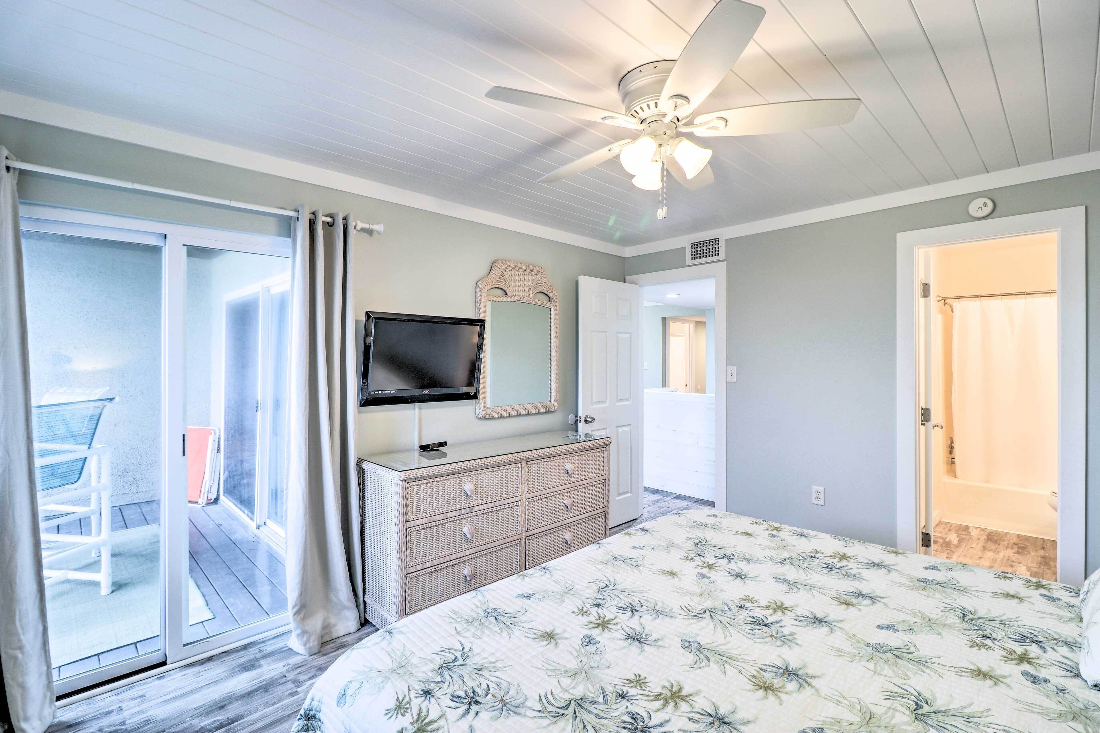 A bedroom with a bed, a dresser, a television, and a ceiling fan.