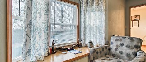 A cozy living room with a window, a sofa, and a wooden console table with decorative items.