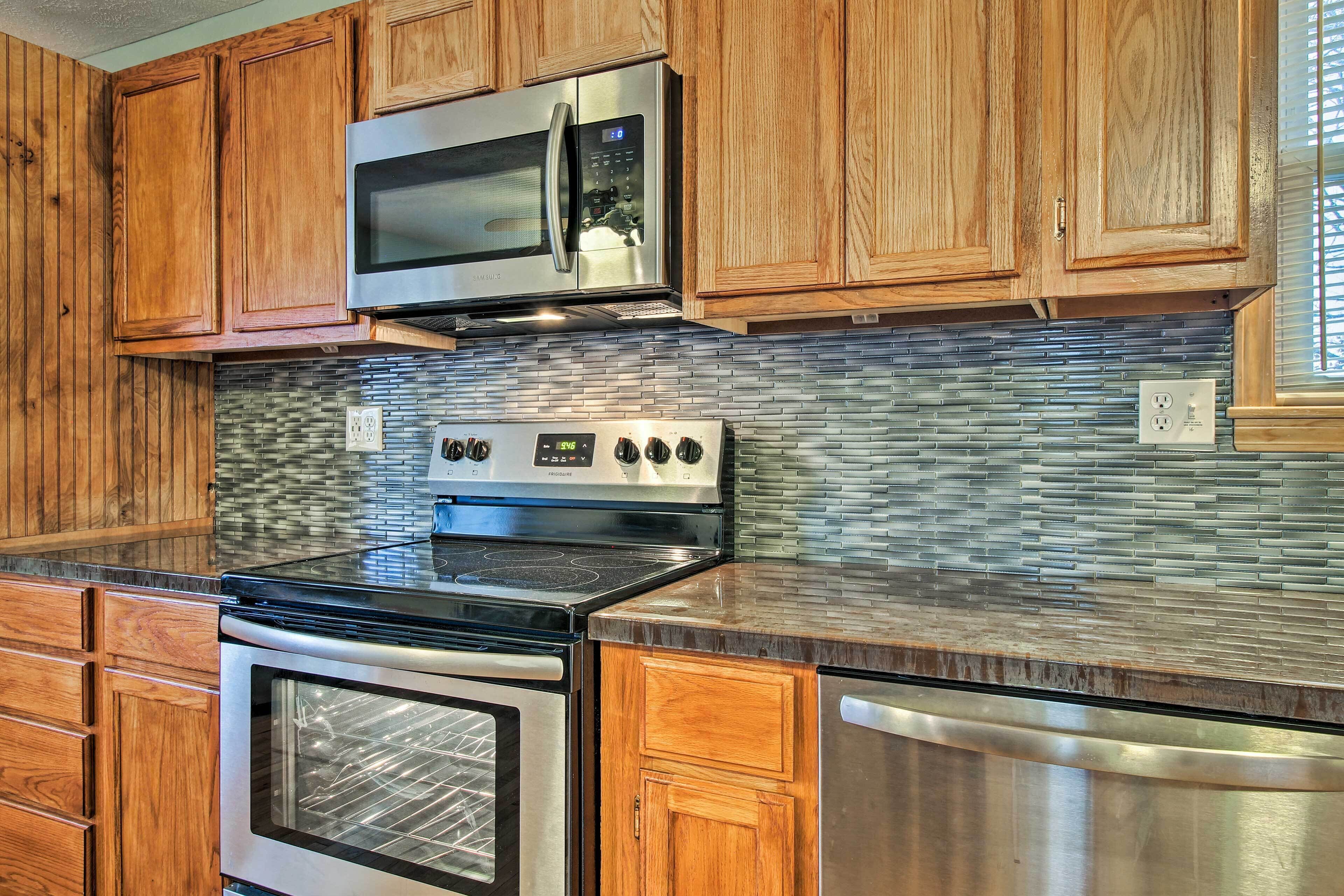 A kitchen with wooden cabinets, a stainless steel microwave, a stove, and an oven.
