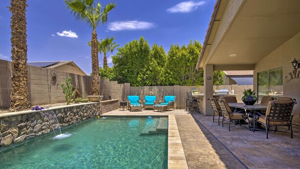 Un jardin avec une piscine, du mobilier de jardin et un espace barbecue.