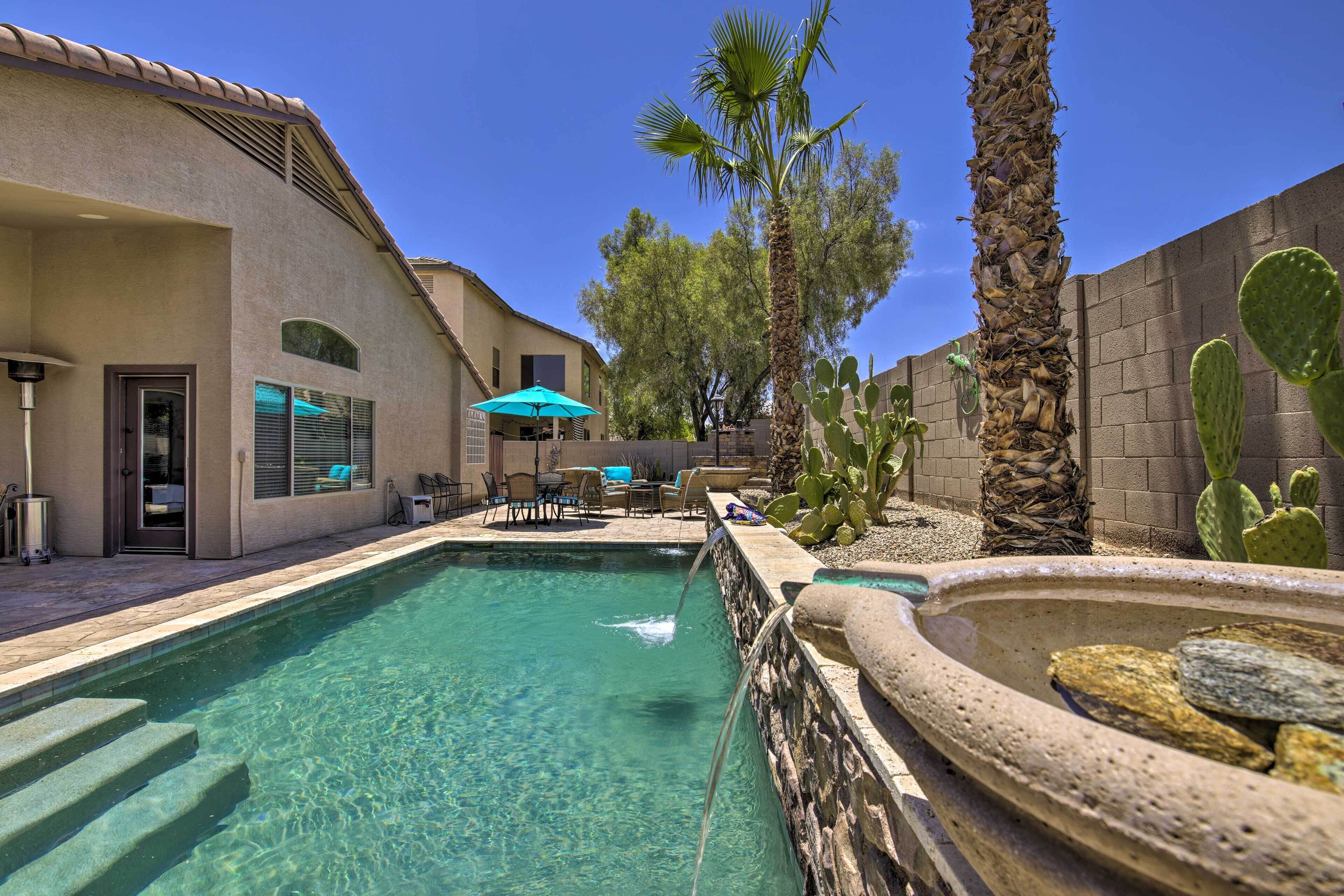Une piscine aux eaux cristallines, accessible par des marches, entourée d’une terrasse aménagée avec des meubles d’extérieur et agrémentée d’un cactus.