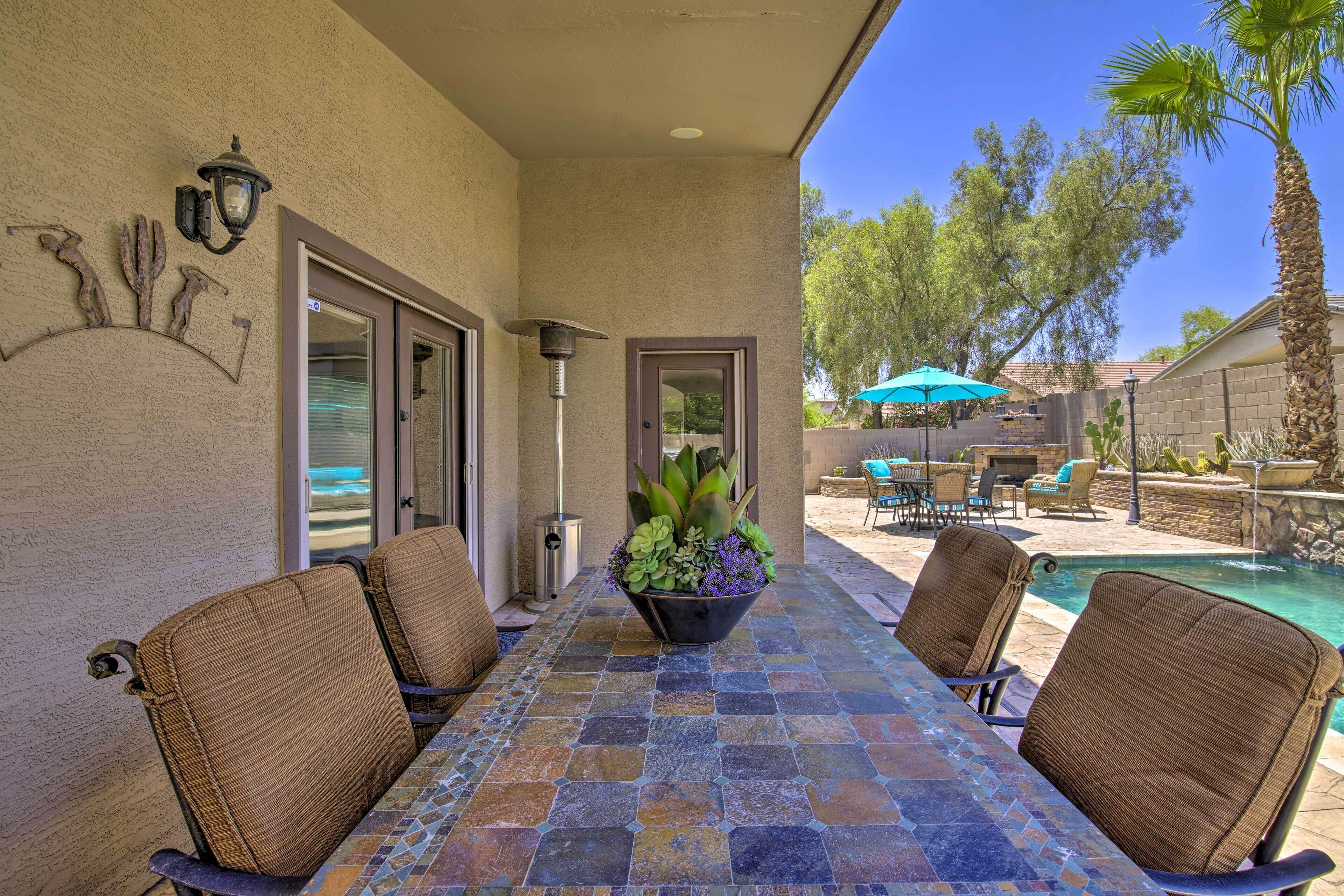 A patio with a table and chairs, a pool, and a view of the surrounding landscape.