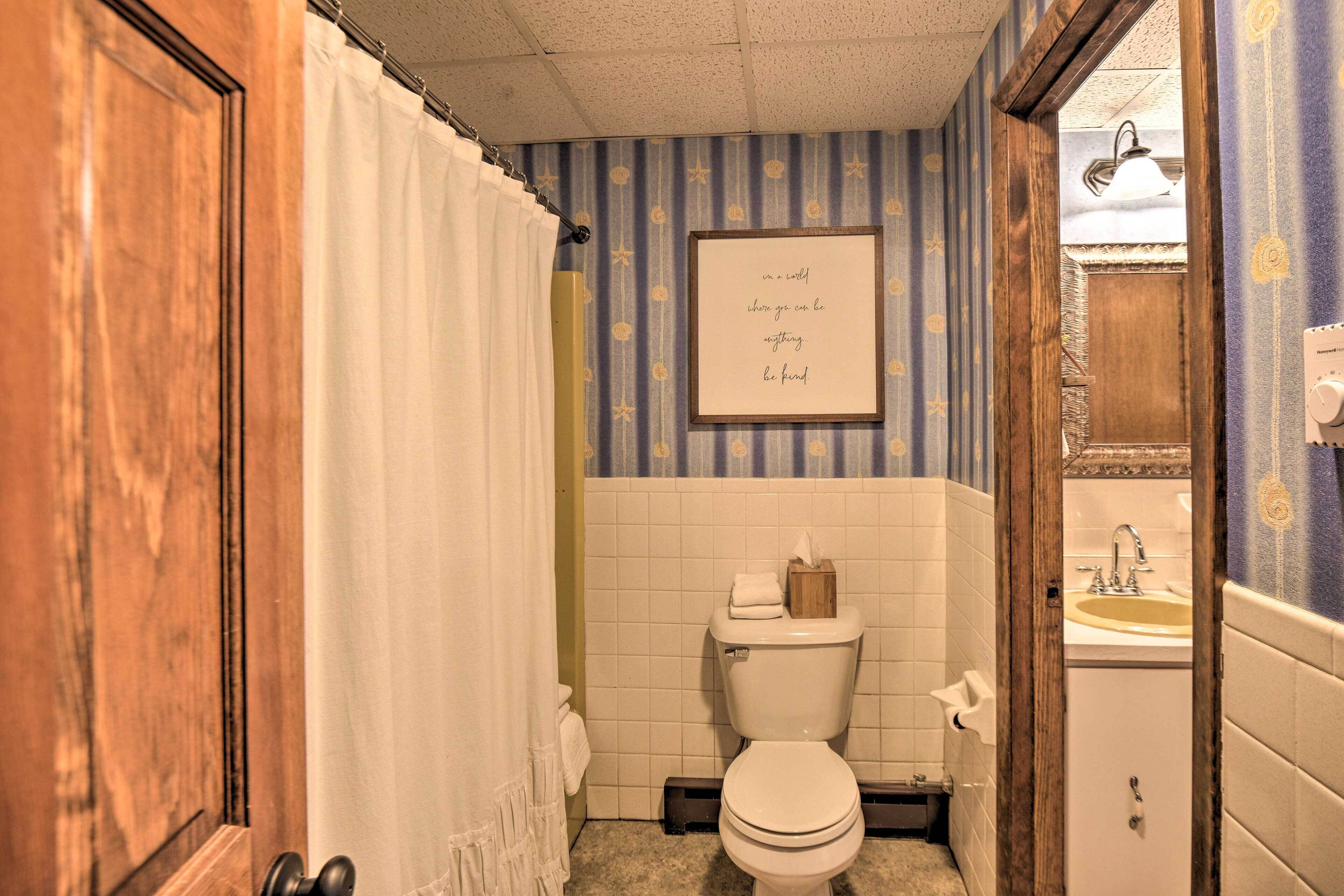 A bathroom with a toilet, a sink, and a framed quote on the wall.