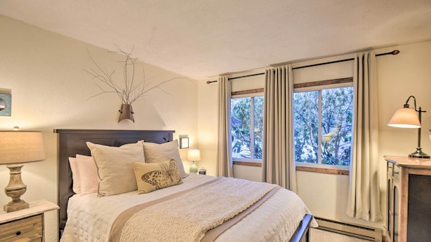 A bedroom with a large bed, a nightstand with a lamp, a dresser, and a window with curtains. - Glen Condo w/ Mountain Views: Walk to Story Land (Glen)