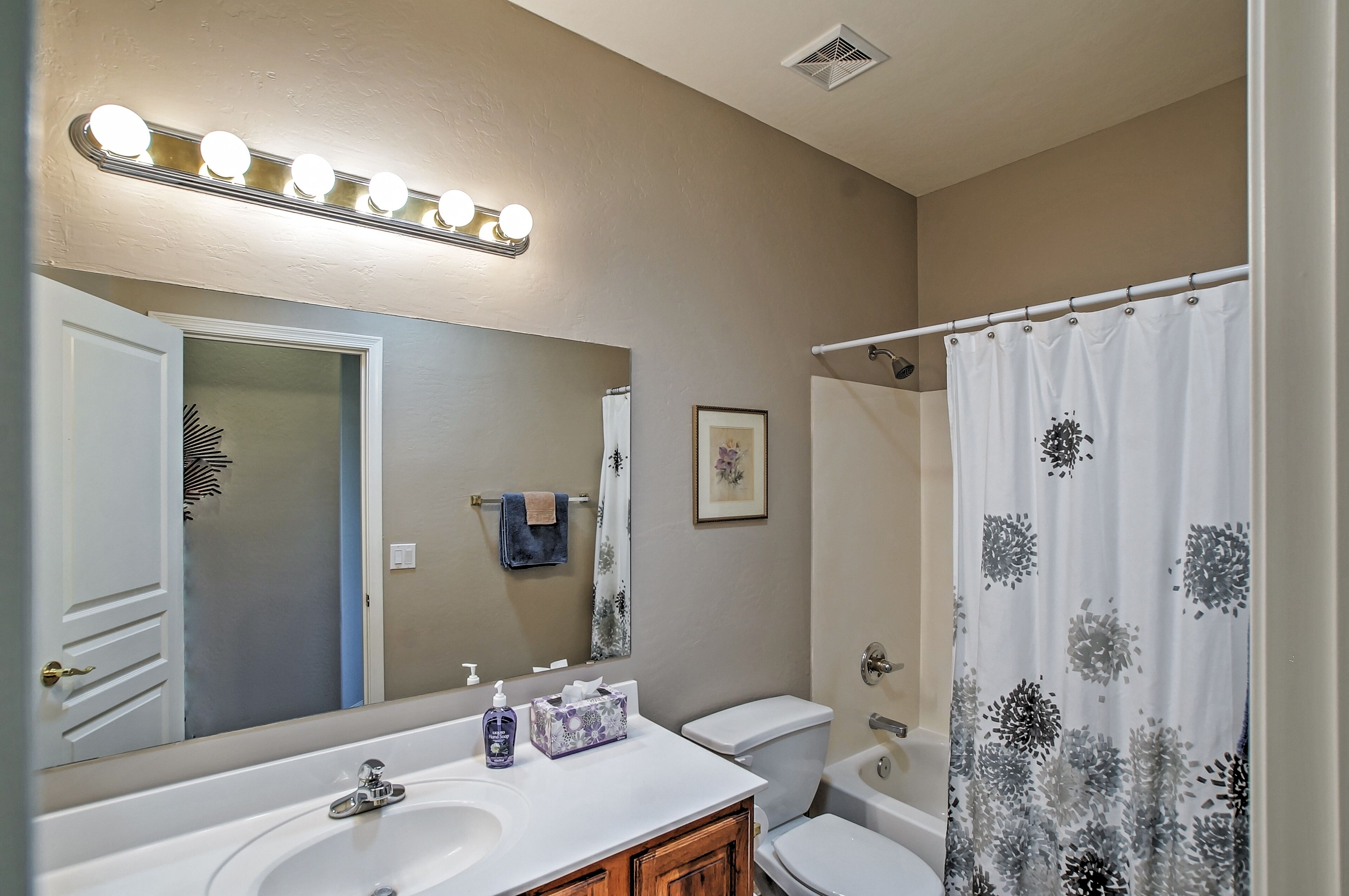 Une salle de bain équipée d’un lavabo, d’un miroir, d’un meuble-lavabo, de toilettes et d’un rideau de douche.