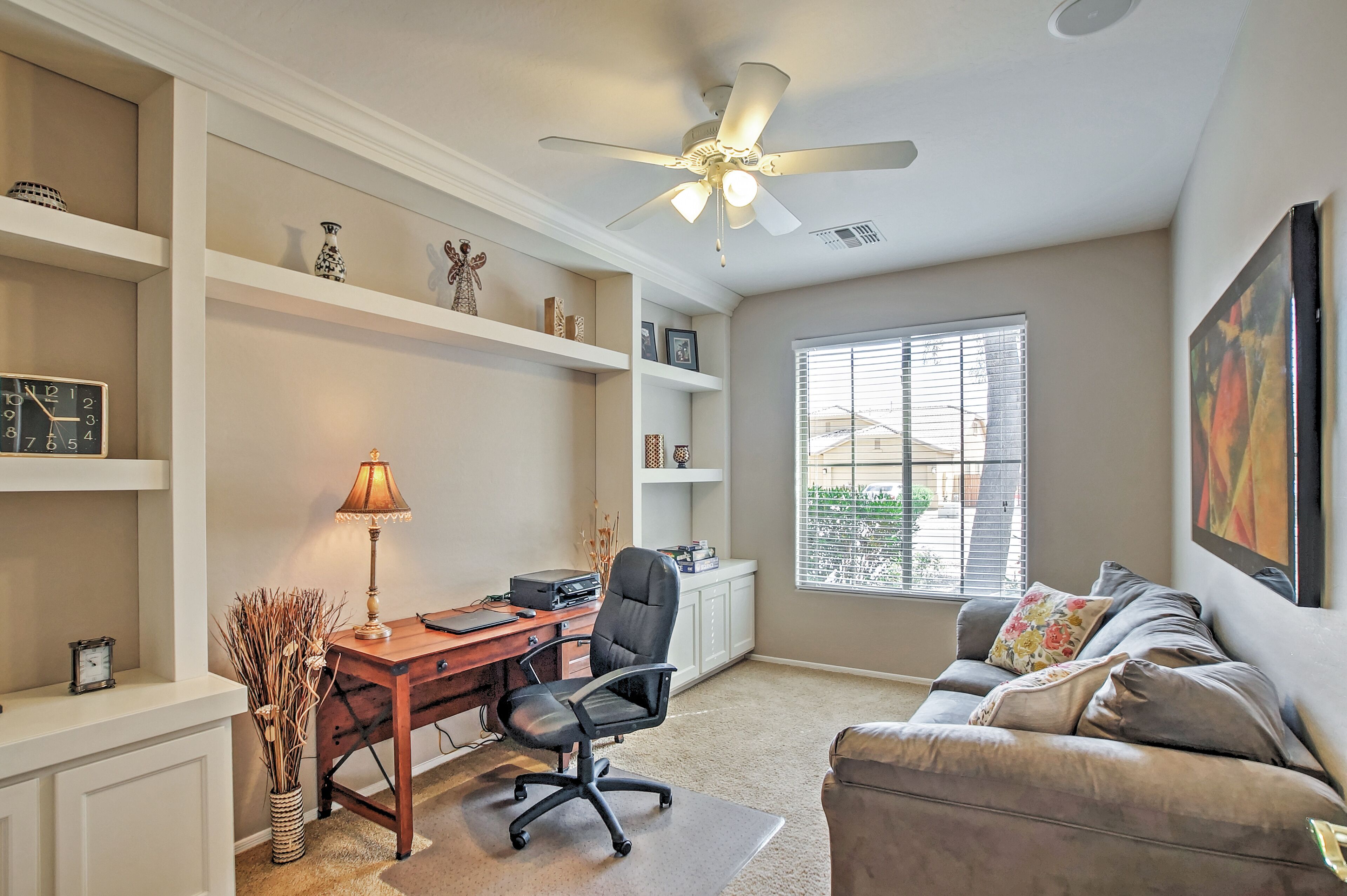 A home office with a desk, chair, and shelves.