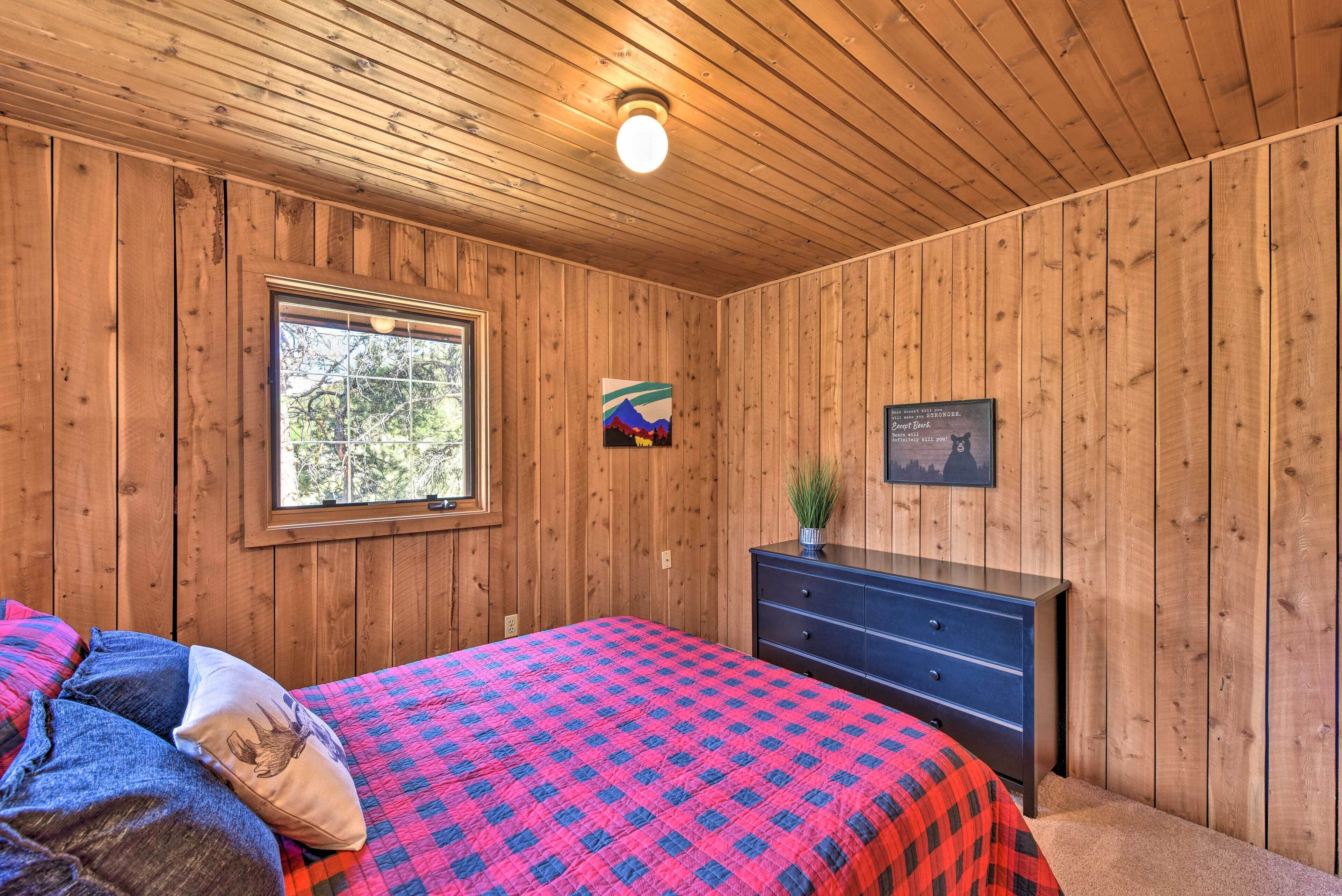 Una habitación con paneles de madera, una cama, un aparador, una ventana y un cuadro en la pared.