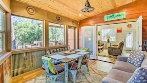Un coin repas avec une table et des chaises en bois, un canapé et une vue sur l’extérieur.