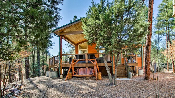 Une cabane dotée d’une terrasse en bois, d’une balançoire et d’un chemin de gravier.