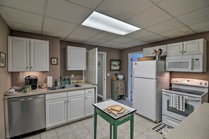 Une cuisine avec des meubles blancs, un four à micro-ondes, une cuisinière et un évier.