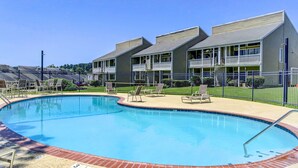 A swimming pool with lounge chairs and a building with balconies in the background. - Gorgeous Lakefront Townhome w/ Pool Access & Views (Montgomery)